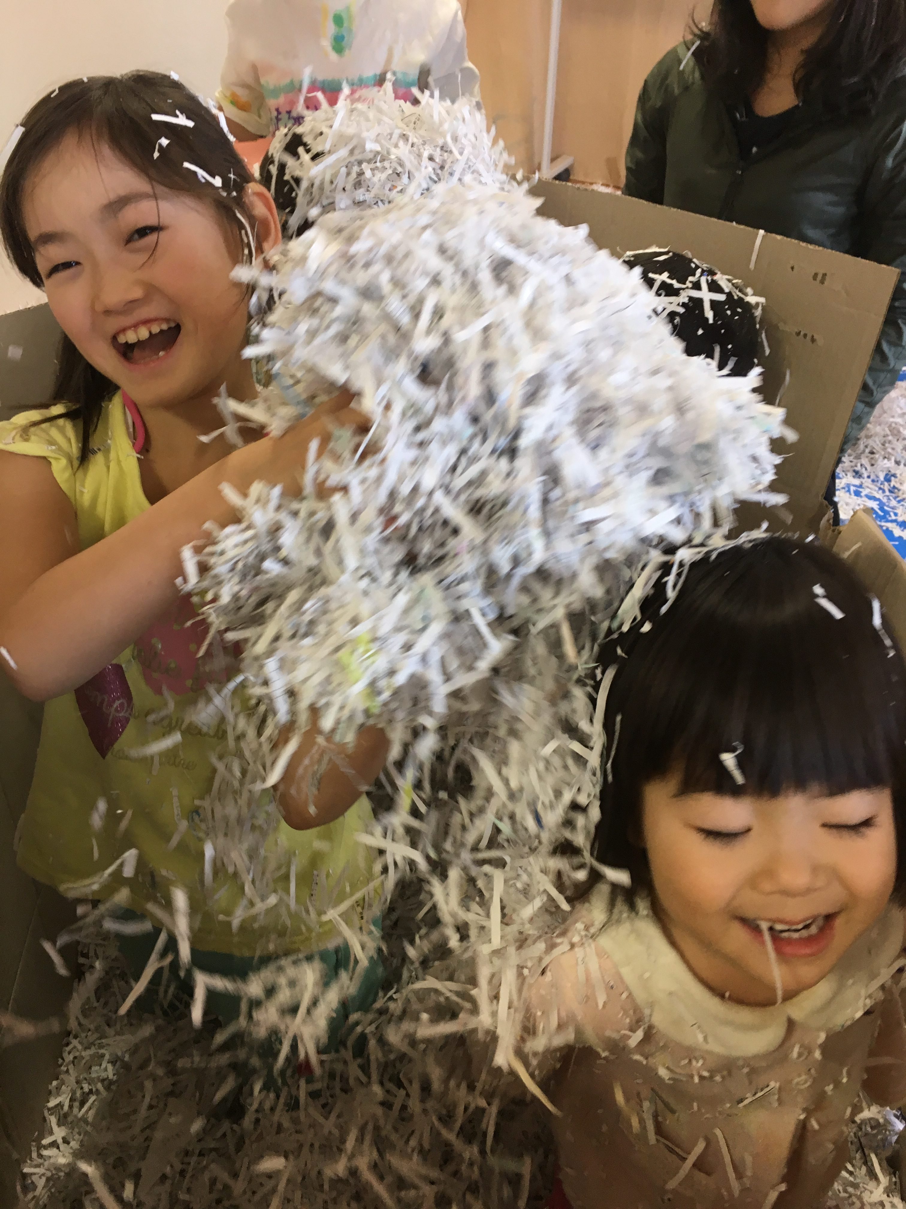 子どものアートセラピー教室でシュレッダーで裁断した紙で遊ぶ子どもたちの様子